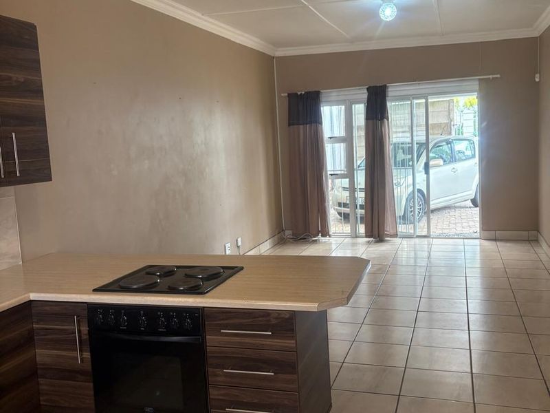 Open-plan living and kitchen area featuring tiled floors, built-in oven and hob, and sliding door access to the exterior.