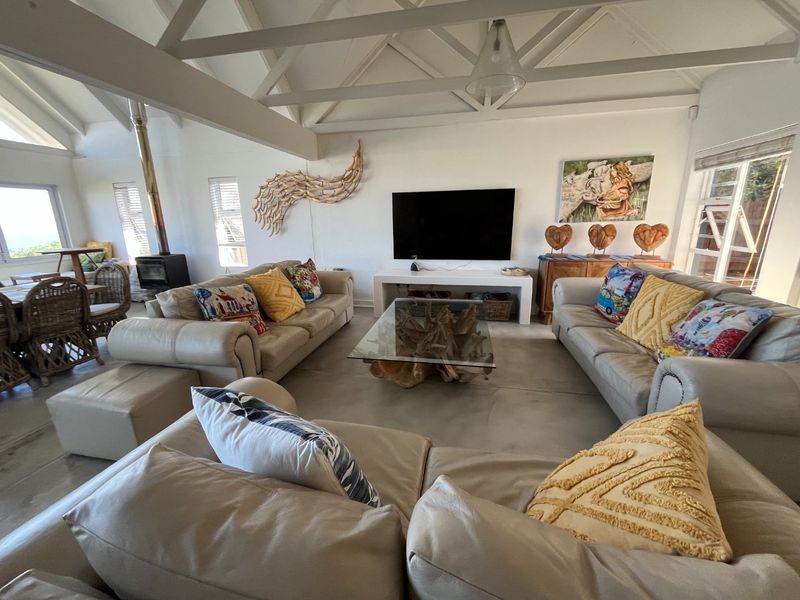 Spacious living room featuring a high vaulted ceiling with exposed timber trusses, a wood-burning fireplace, and polished concrete flooring.