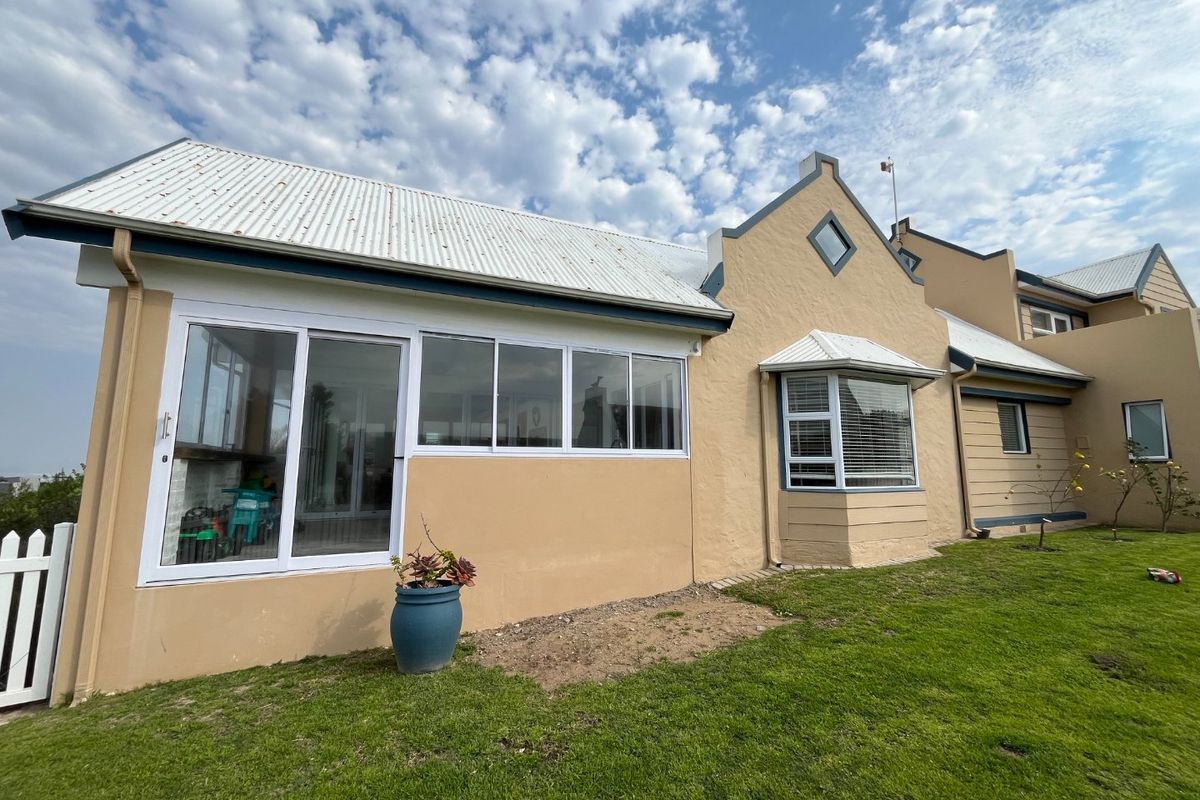 Rear view of a house featuring a corrugated metal roof, sliding glass doors, and a bay window overlooking a lawn.