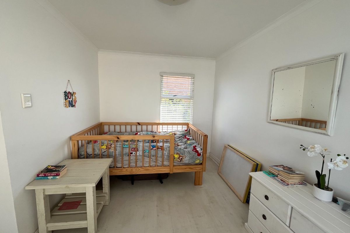 A bedroom featuring white walls, light-toned flooring, venetian blinds, and coving detail.