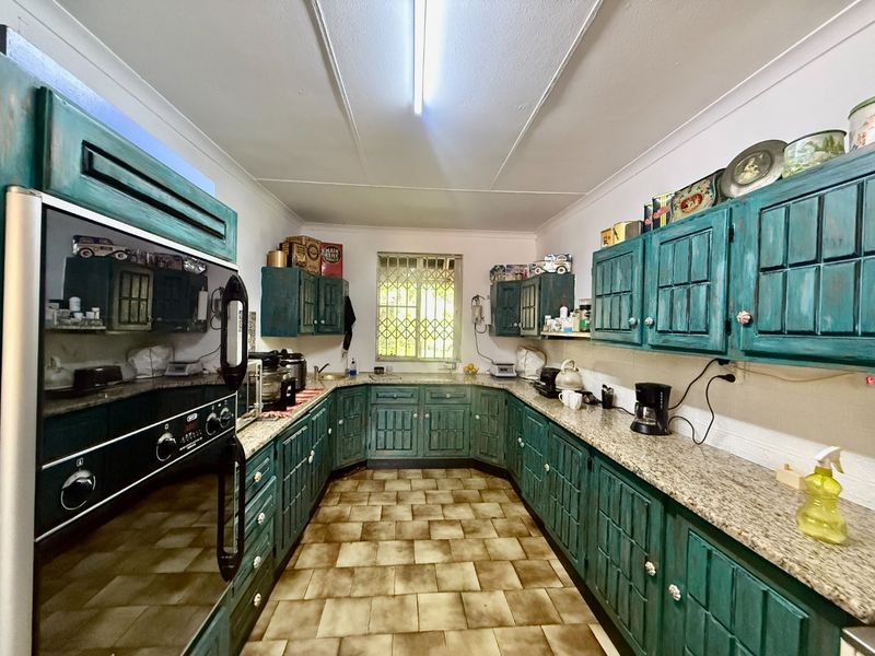 A functional kitchen featuring U-shaped cabinetry with granite countertops, built-in oven, and tiled flooring, offering a classic layout with potential for modern updates.