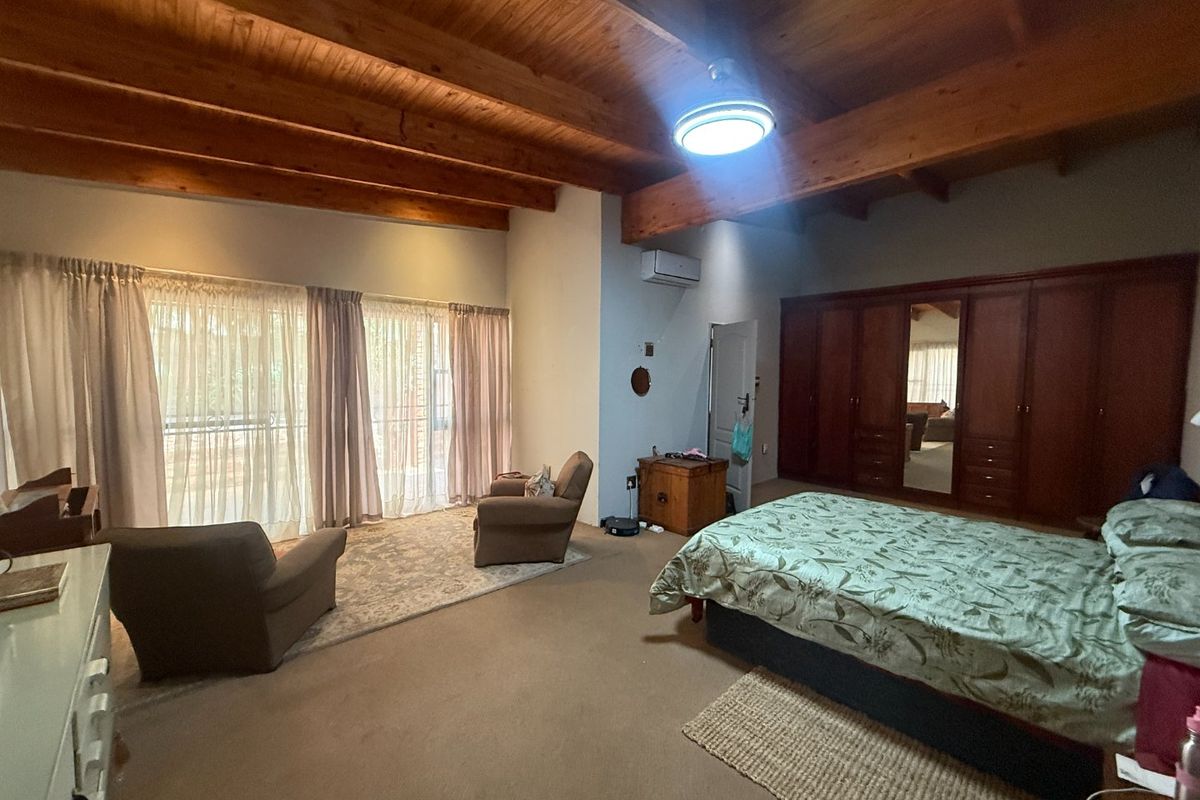 Spacious bedroom featuring exposed timber ceiling beams, built-in wooden cabinetry, and large sliding glass doors providing access to the exterior.
