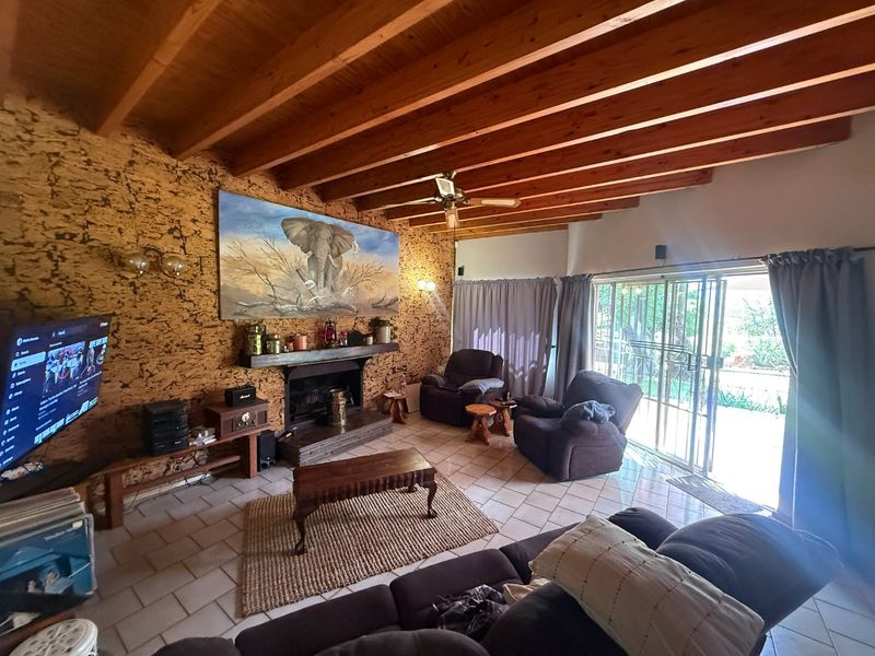 Spacious living room featuring exposed timber ceiling beams, unique cork wall cladding, a fireplace, and direct access to the patio through sliding glass doors.
