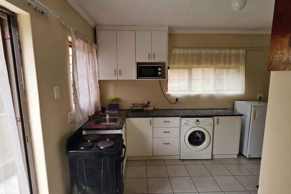 Functional kitchen featuring white cabinetry, laminate countertops, tiled flooring, and integrated laundry plumbing, offering a practical layout for daily use.