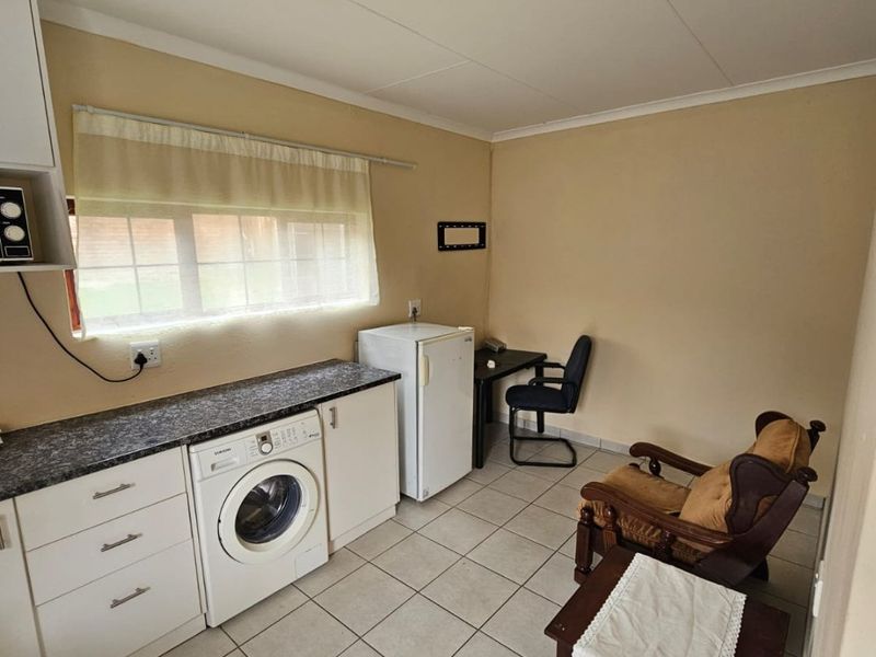 A functional laundry room featuring tiled flooring, built-in cabinetry with a laminate countertop, and space for a washing machine.