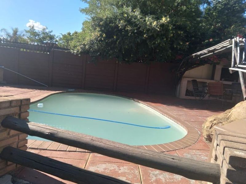 Outdoor pool area featuring a swimming pool, brick paving, and a built-in braai area, enclosed by perimeter fencing.