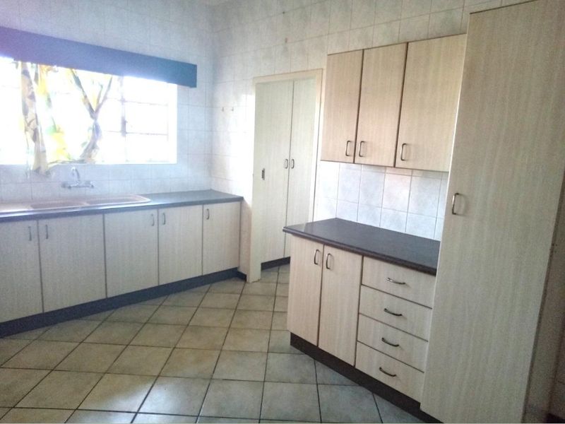 A functional kitchen featuring laminate cabinetry, ample counter space, a double basin sink, and tiled flooring throughout.