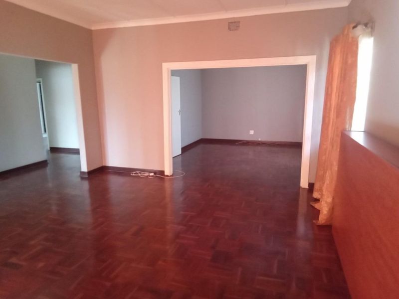 Spacious living area featuring classic parquet flooring and an open-plan layout with connecting archways, providing a versatile blank canvas for interior design.
