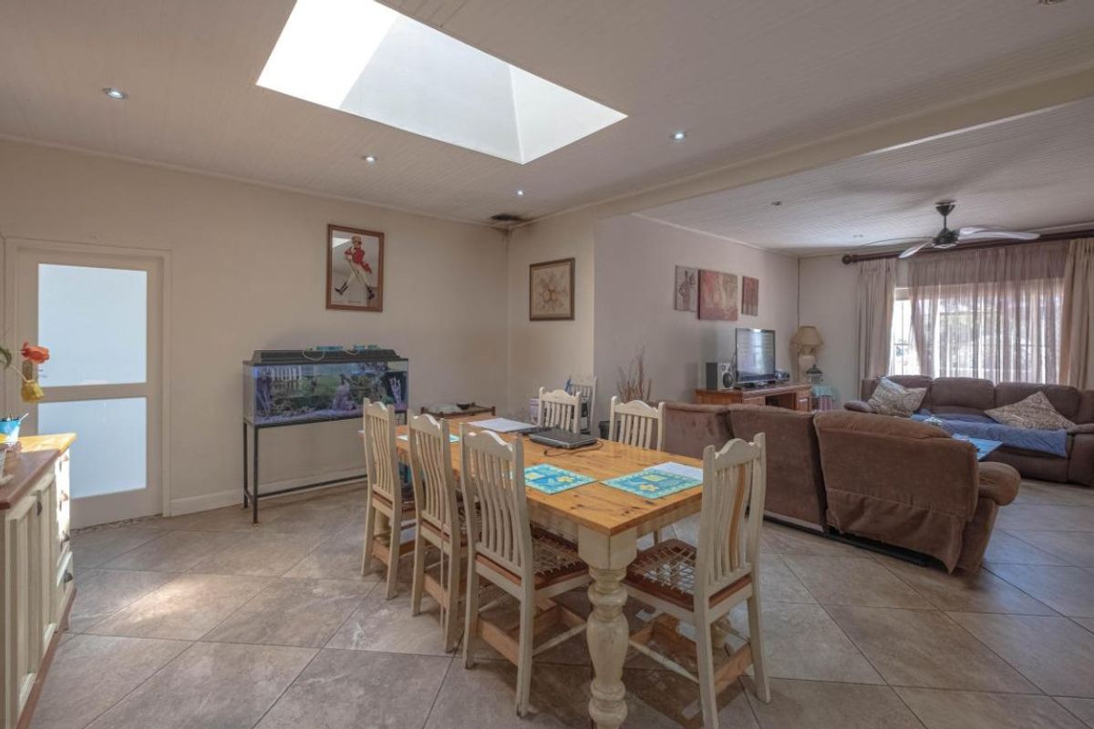 Spacious open-plan living and dining area featuring tiled flooring, a large skylight, and a ceiling fan, creating a bright and functional family space.