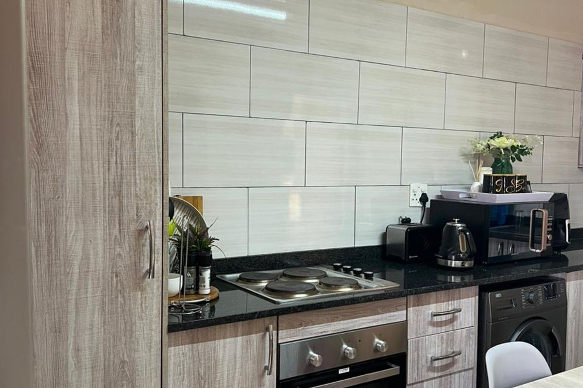 Modern kitchen featuring wood-grain cabinetry, granite countertops, built-in oven and hob, and a clean subway tile backsplash.