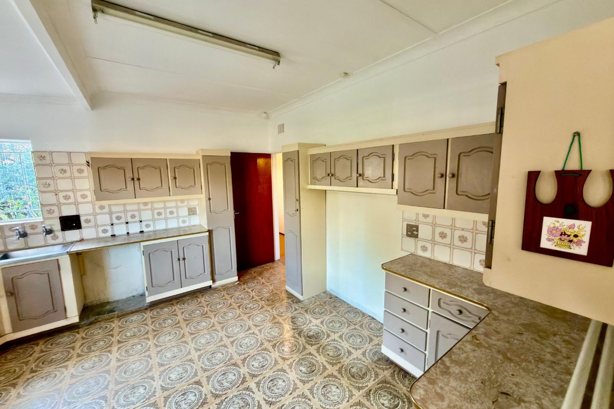 A dated kitchen featuring original cabinetry, patterned vinyl flooring, and tiled backsplash, offering significant potential for a modern renovation.