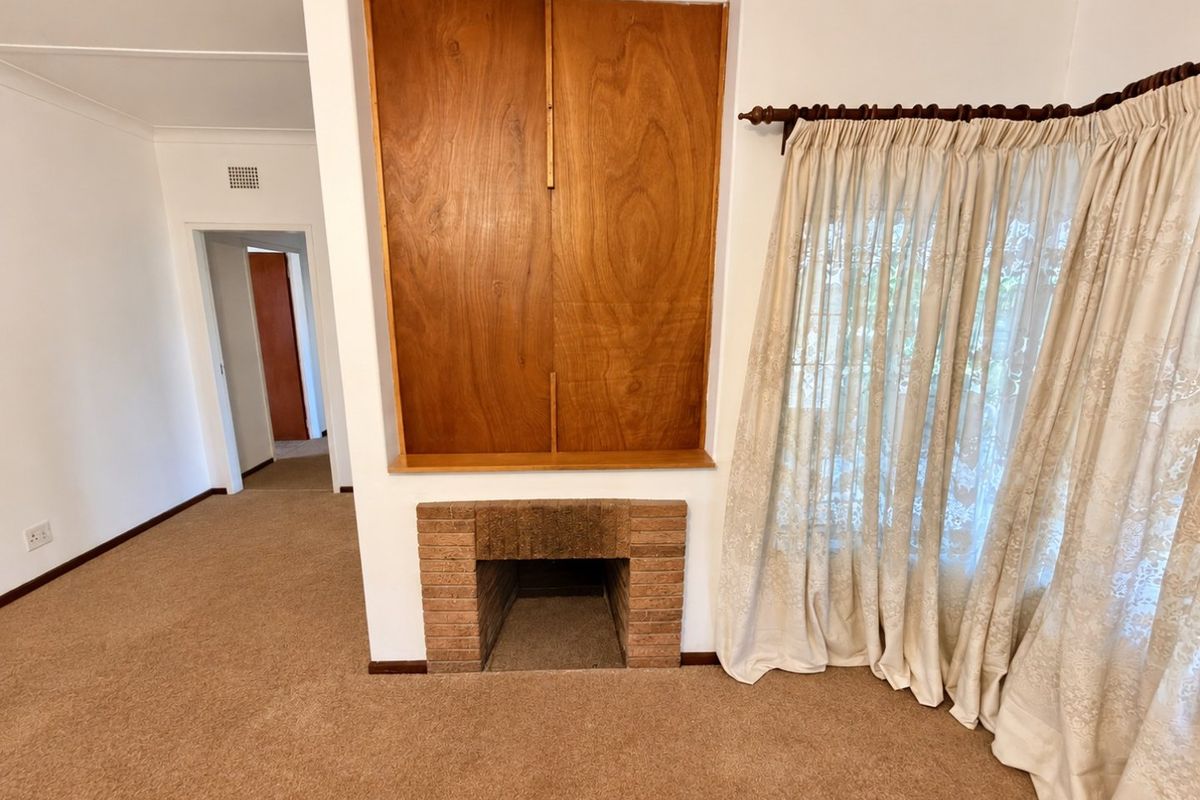 A living room featuring a brick fireplace and built-in wooden cabinetry, finished with neutral carpeting and cove cornicing.
