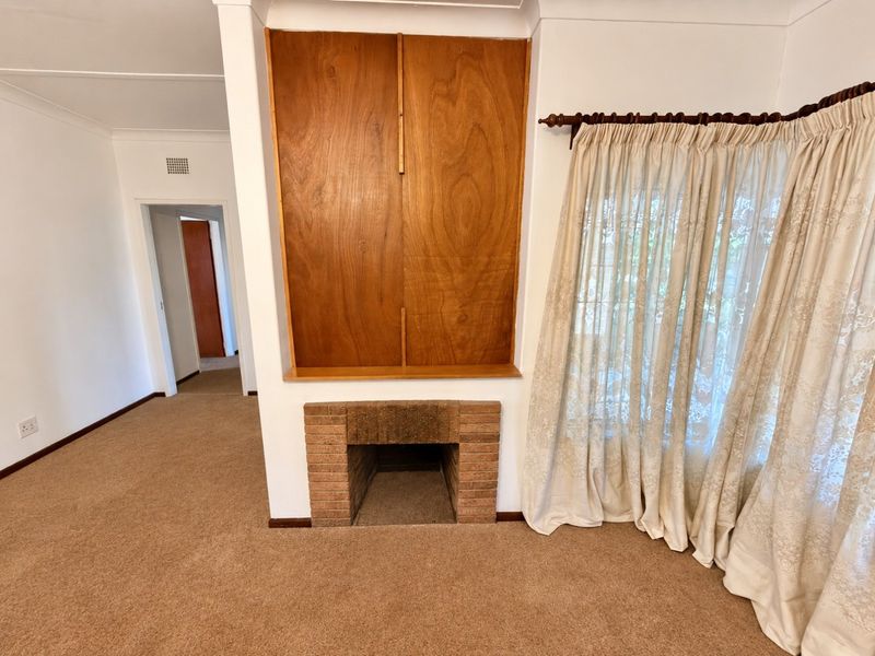 A living room featuring a brick fireplace and built-in wooden cabinetry, finished with neutral carpeting and cove cornicing.