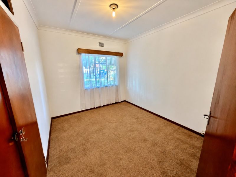 A clean, empty bedroom featuring neutral walls, carpet flooring, and a timber window pelmet, offering a blank canvas for personalization.