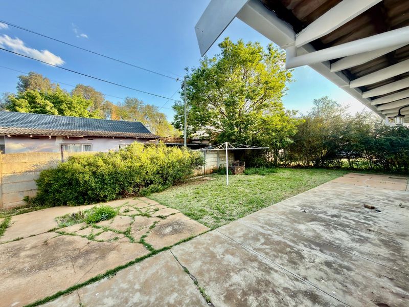 Rear garden area featuring a concrete patio, lawn, and brick boundary wall, providing a functional outdoor space with potential for landscaping improvements.