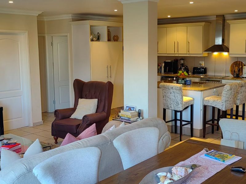 Spacious open-plan living area featuring a modern kitchen with stone countertops, built-in cabinetry, and recessed lighting, seamlessly flowing into the dining and lounge space.