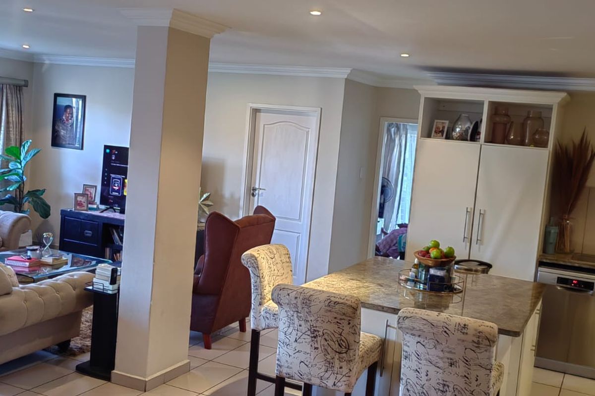 Spacious open-plan living area featuring a modern kitchen with stone countertops, integrated appliances, and seamless flow to the lounge and outdoor access.
