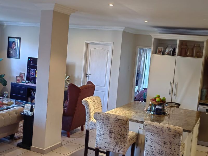 Spacious open-plan living area featuring a modern kitchen with stone countertops, integrated appliances, and seamless flow to the lounge and outdoor access.
