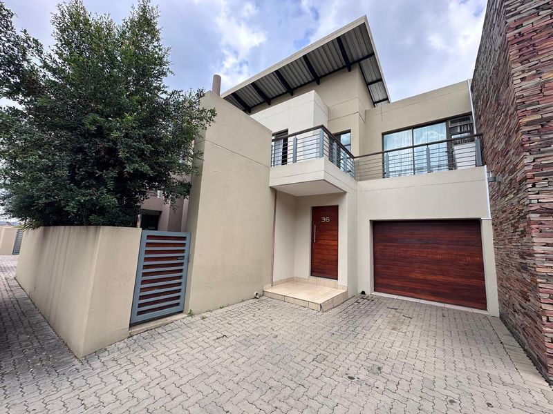 Modern double-story residence featuring a paved driveway, timber garage door, and a private balcony with contemporary architectural finishes.