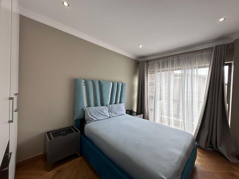 A well-maintained bedroom featuring hardwood flooring, recessed downlights, and a sliding glass door providing access to an outdoor area.
