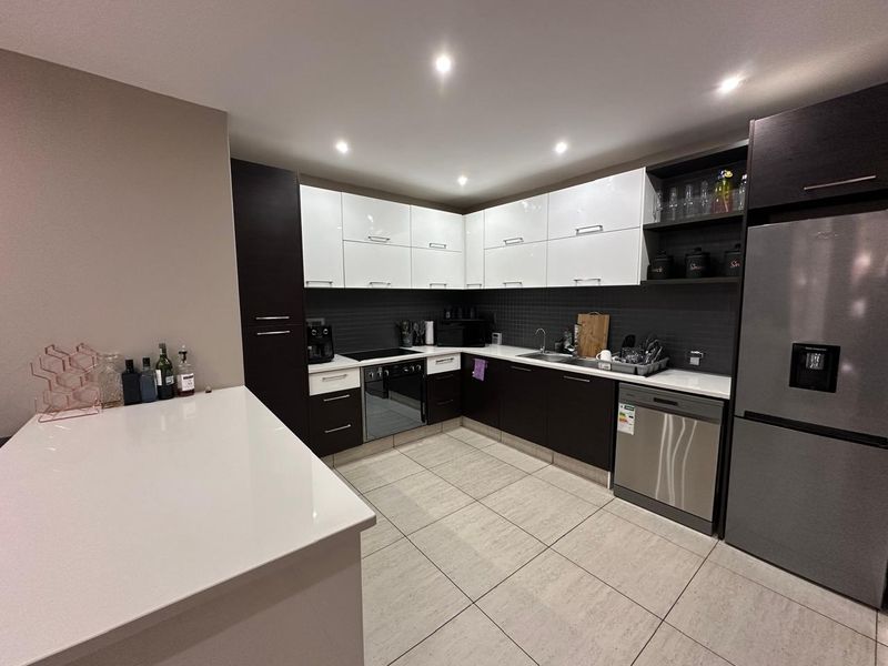 Modern kitchen featuring high-gloss cabinetry, stone countertops, integrated appliances, and tiled flooring with recessed lighting.