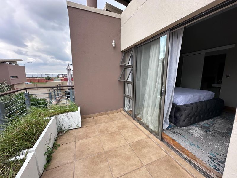 A private balcony featuring tiled flooring, built-in planters, and a sliding glass door providing seamless access to the adjacent bedroom.