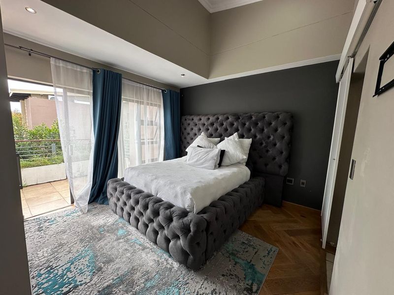 A well-maintained bedroom featuring herringbone timber flooring, recessed lighting, and direct access to a private balcony through sliding glass doors.
