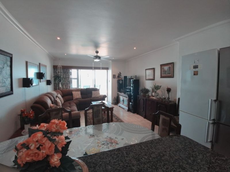 Open plan living and dining area featuring recessed lighting, a ceiling fan, and a granite breakfast bar, with access to a balcony.
