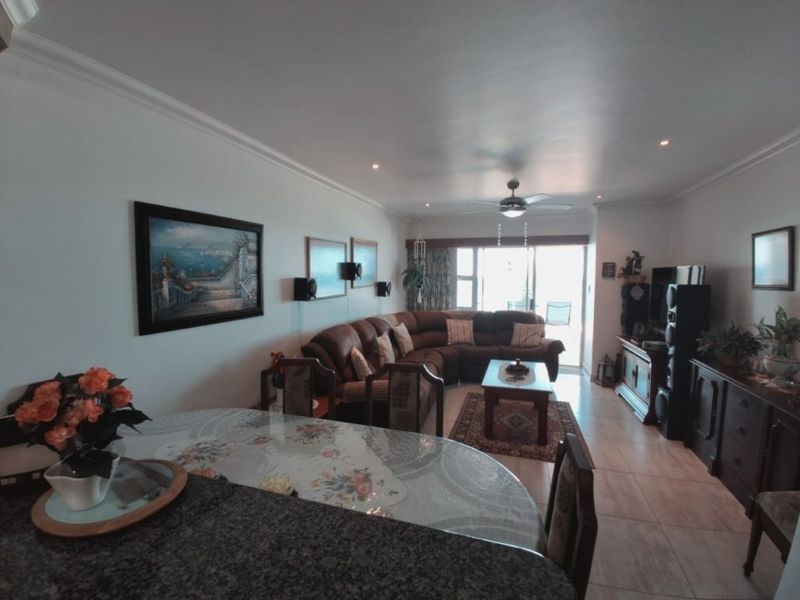 Spacious open-plan living and dining area featuring tiled flooring, recessed lighting, a ceiling fan, and direct access to a balcony through sliding glass doors.