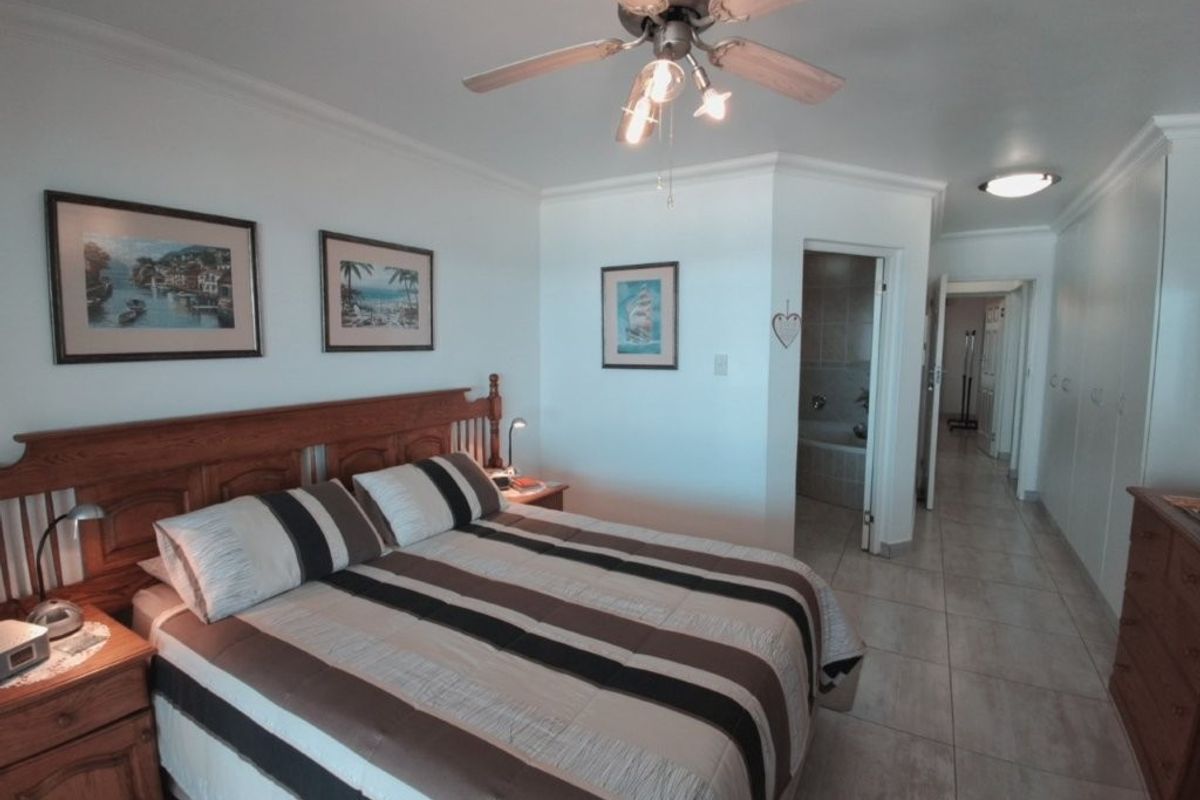 Spacious bedroom featuring tiled flooring, a ceiling fan, and built-in cupboards, with direct access to an en-suite bathroom.