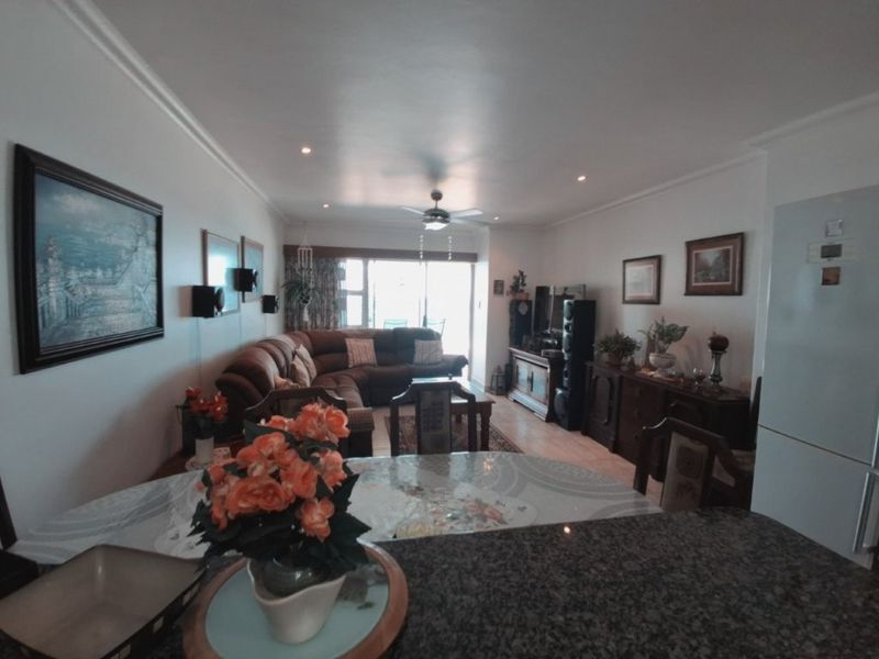 Open plan living and dining area featuring a granite breakfast bar, recessed lighting, ceiling fan, and sliding glass doors leading to the balcony.