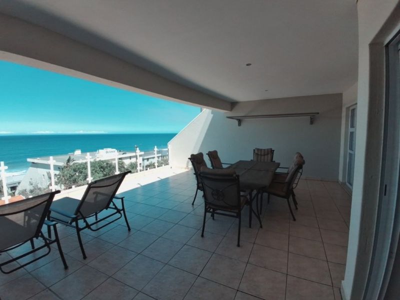 Spacious covered balcony featuring tiled flooring and expansive ocean views, providing an ideal outdoor space for relaxation and entertaining.