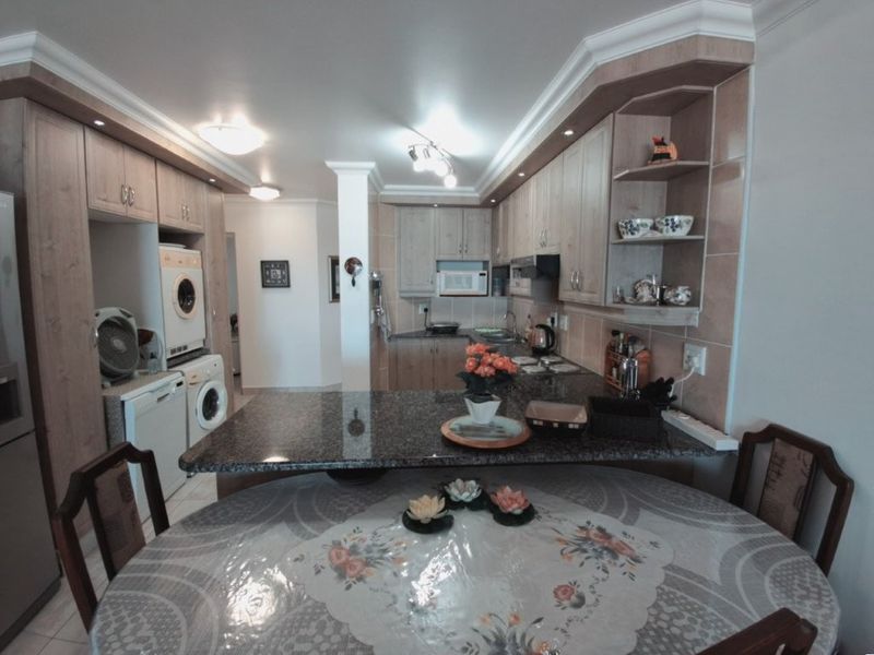 Open-plan kitchen and dining area featuring granite countertops, extensive built-in cabinetry, and integrated laundry facilities in a well-maintained apartment setting.