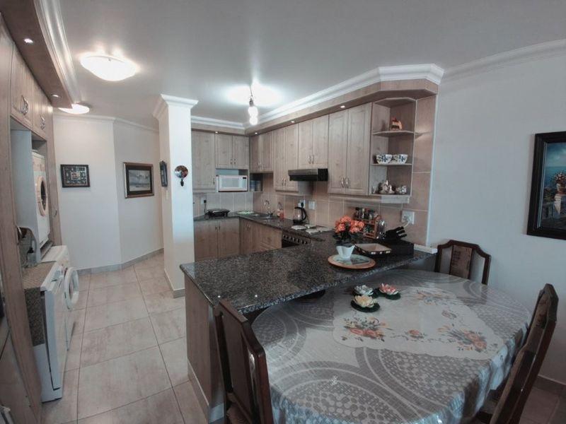 Open-plan kitchen and dining area featuring granite countertops, ample built-in cabinetry, and tiled flooring, creating a functional and cohesive living space.