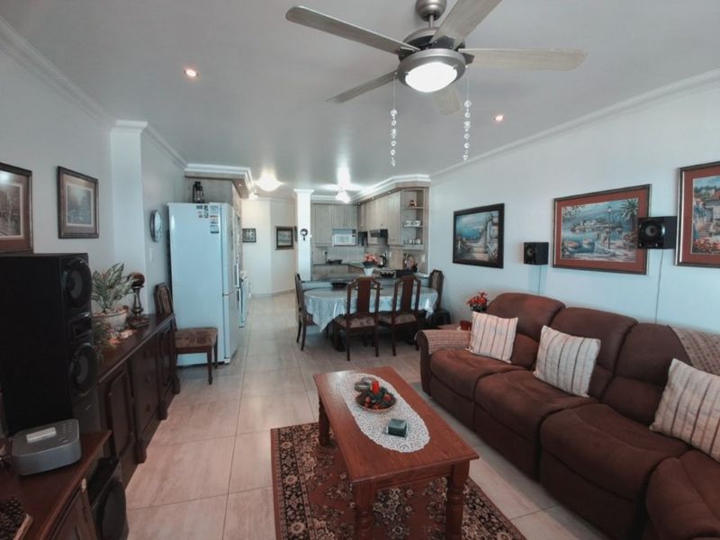 Spacious open-plan living and dining area featuring tiled floors, recessed lighting, a ceiling fan, and a functional kitchen with built-in cabinetry.