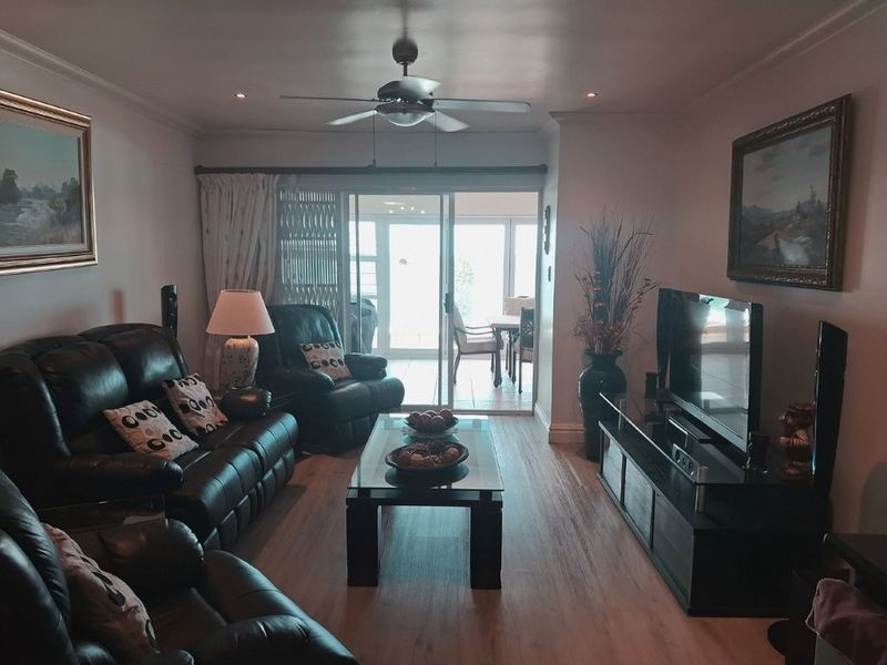 A comfortable living room featuring laminate flooring, recessed lighting, a ceiling fan, and sliding glass doors leading to an outdoor patio area.