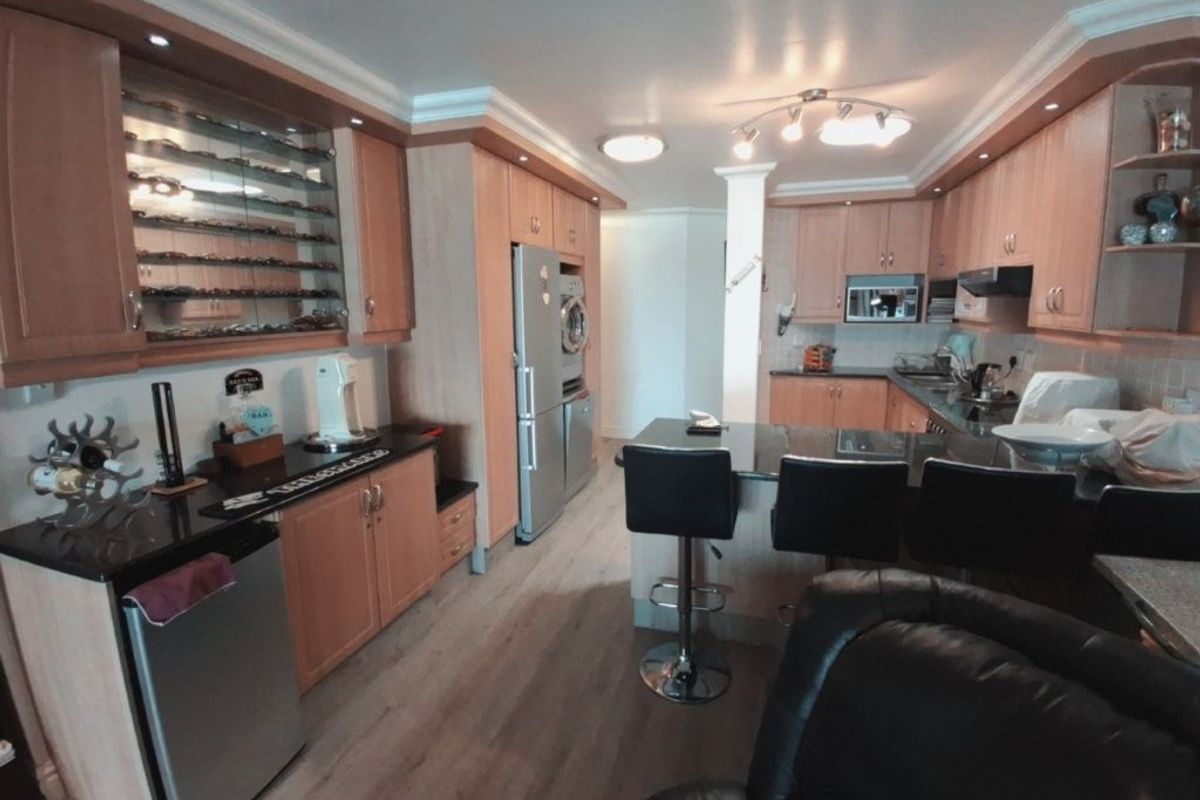 A functional kitchen featuring light wood cabinetry, granite countertops, a breakfast bar, and integrated appliances, offering a practical layout for cooking and dining.