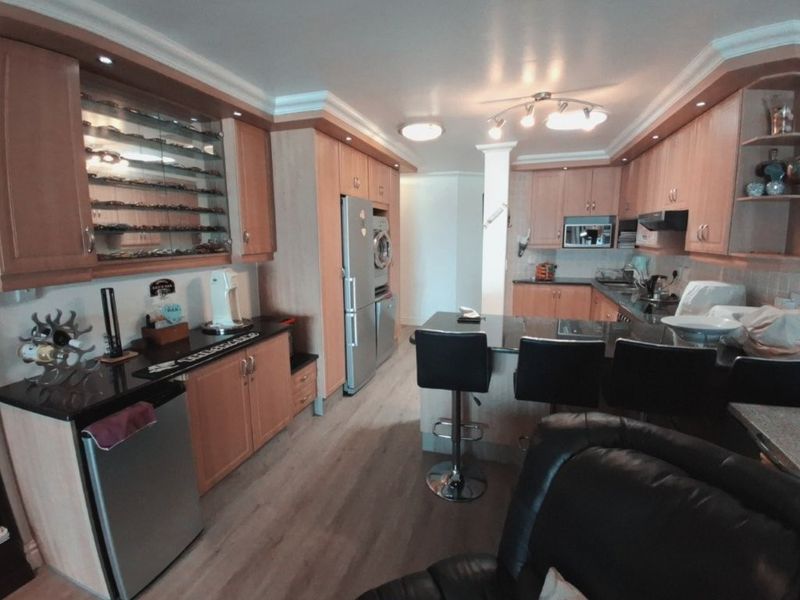 A functional kitchen featuring light wood cabinetry, granite countertops, a breakfast bar, and integrated appliances, offering a practical layout for cooking and dining.