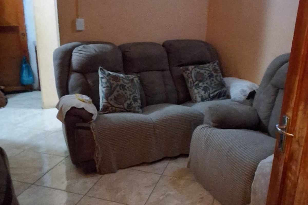 A living room area featuring tiled flooring and a wooden door, providing a functional space for relaxation.
