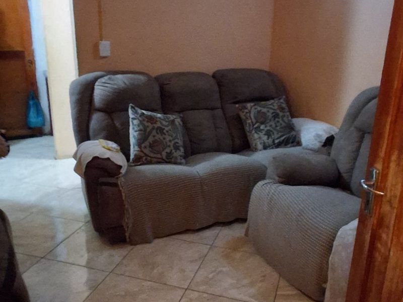A living room area featuring tiled flooring and a wooden door, providing a functional space for relaxation.