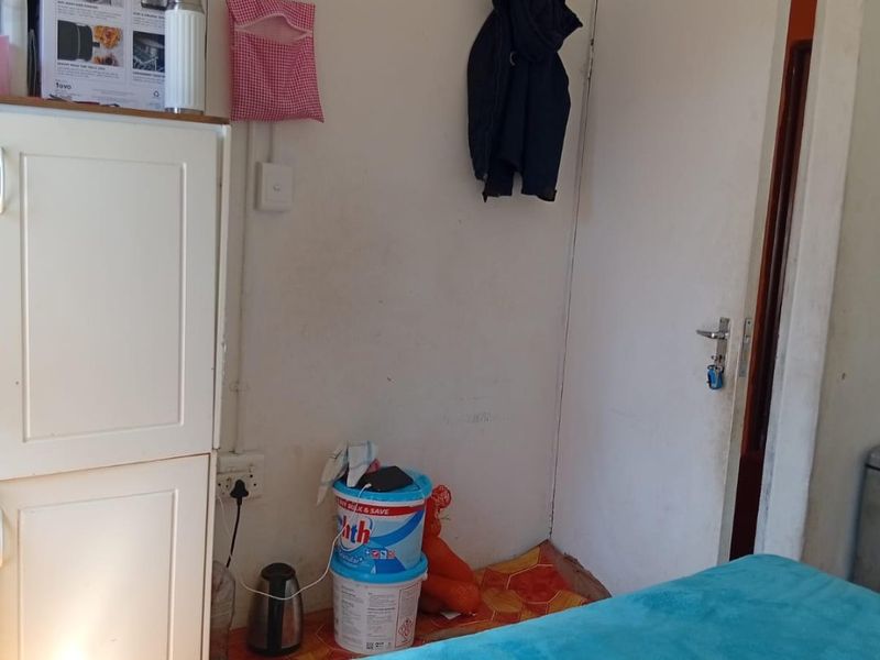 A bedroom interior featuring a standard door and basic electrical fixtures, currently used for storage and living space.