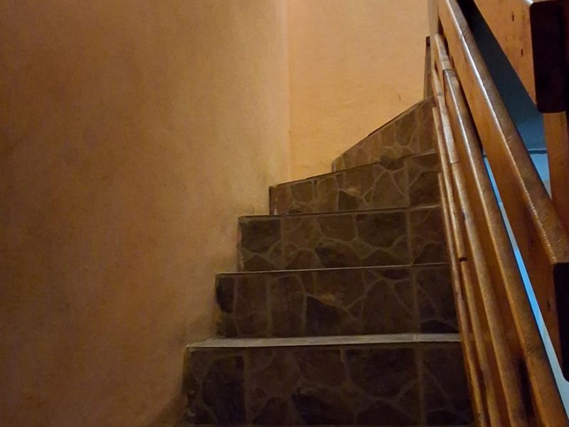 A staircase featuring stone-tiled steps and a wooden balustrade, providing access between levels.