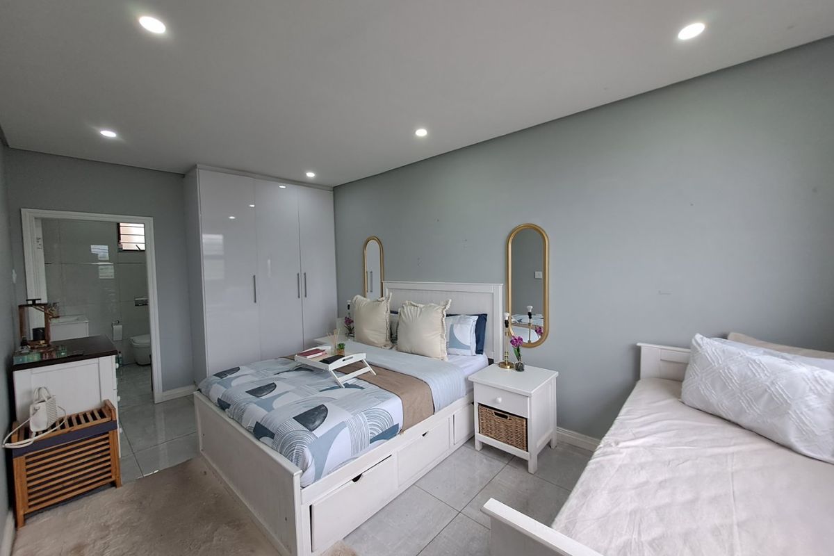 A well-maintained bedroom featuring tiled flooring, recessed downlights, and built-in cupboards, with convenient access to an adjoining en-suite bathroom.