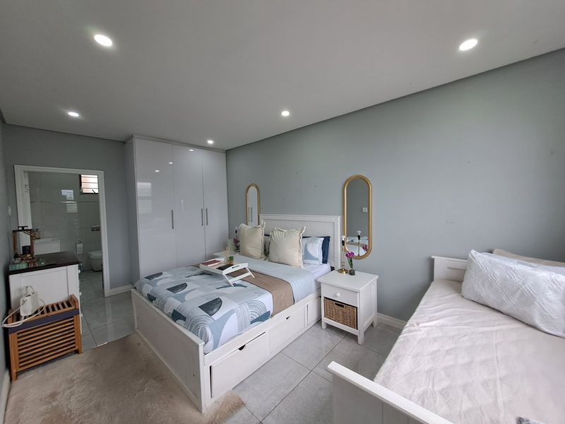 A well-maintained bedroom featuring tiled flooring, recessed downlights, and built-in cupboards, with convenient access to an adjoining en-suite bathroom.