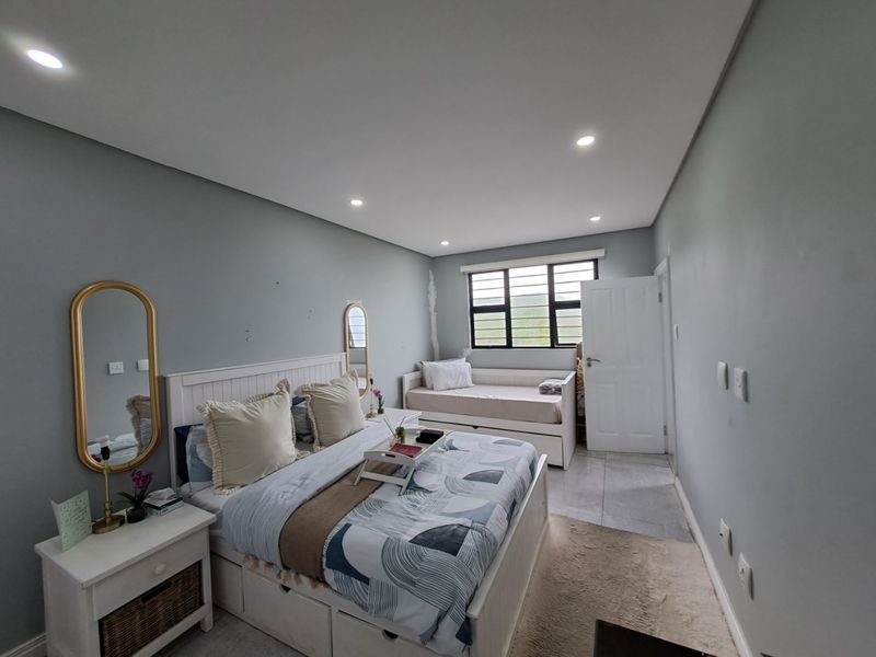 A bedroom featuring tiled flooring, recessed downlighting, and a louvered window. The space shows minor wear on the walls and window trim.