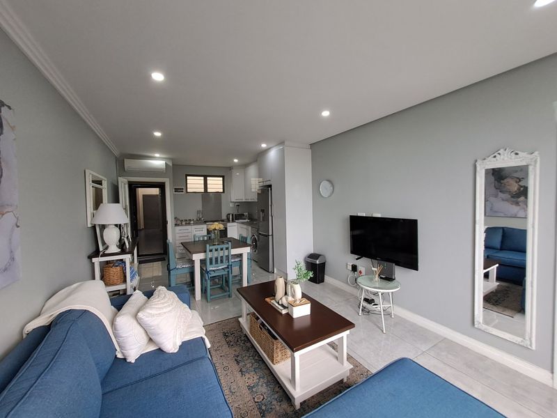 An open-plan living and kitchen area featuring tiled floors, recessed lighting, and a split-system air conditioner, creating a functional and cohesive living space.