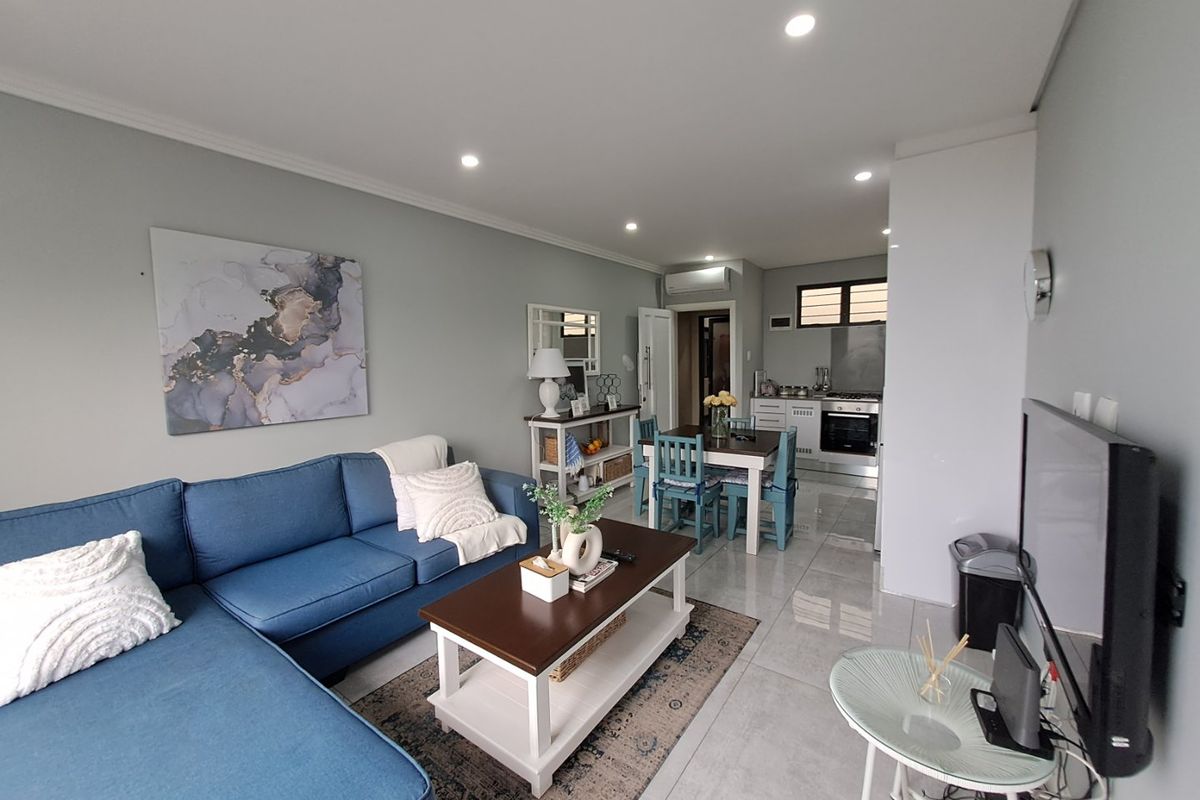An open-plan living and dining area featuring tiled floors, recessed lighting, and a modern kitchen with built-in appliances and cabinetry.