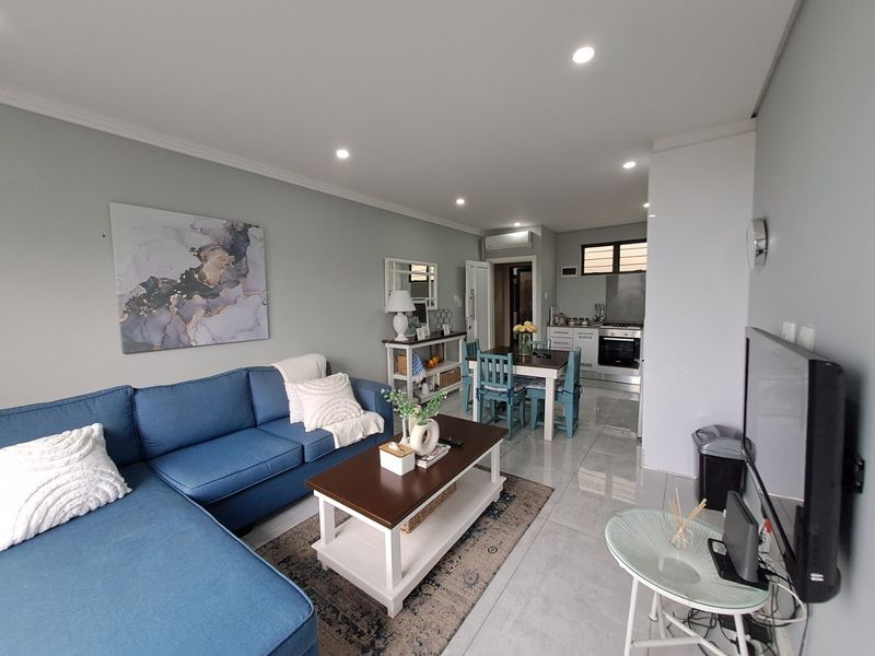 An open-plan living and dining area featuring tiled floors, recessed lighting, and a modern kitchen with built-in appliances and cabinetry.