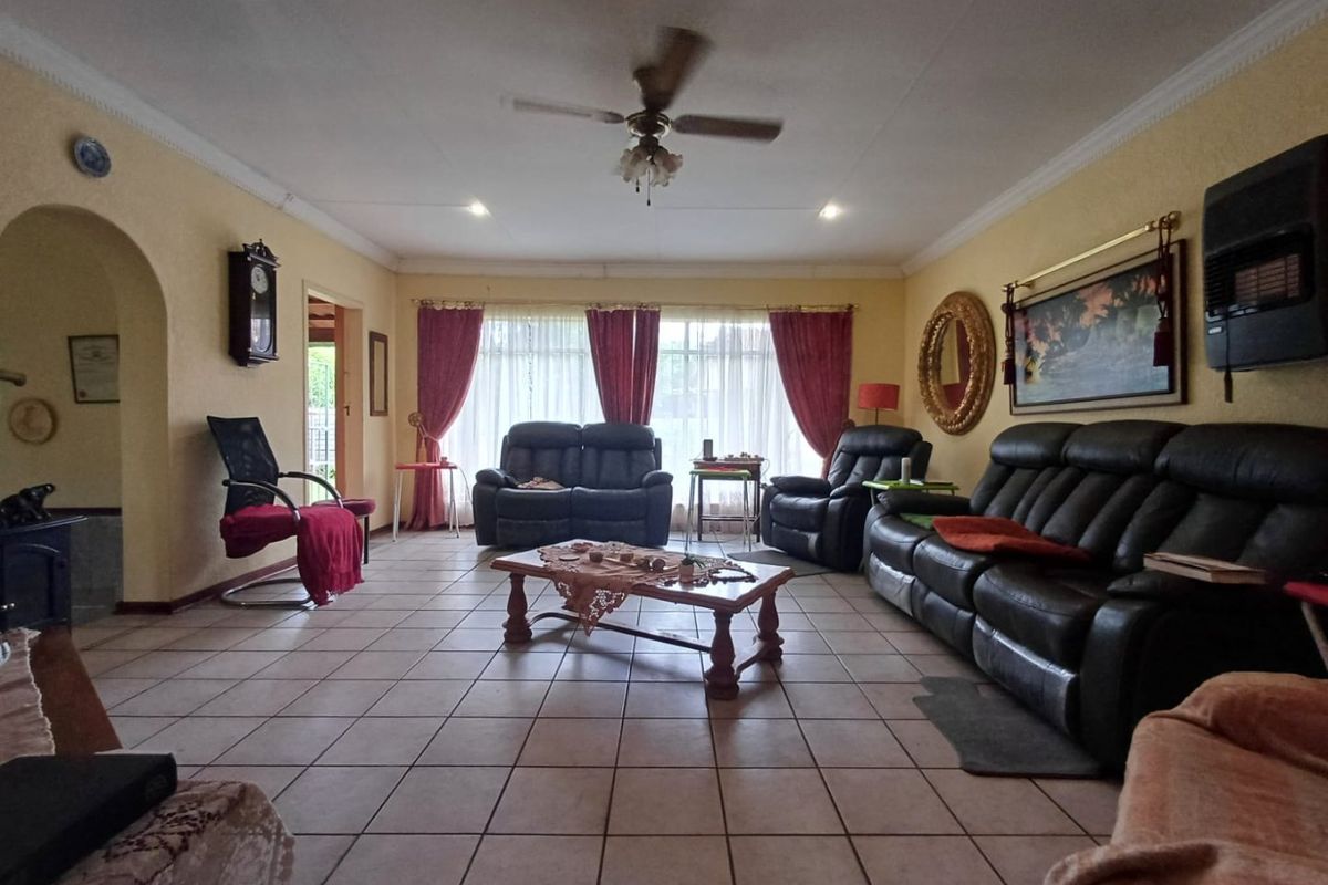 Spacious living room featuring tiled flooring, a ceiling fan, and a wall-mounted heater, offering a comfortable and functional layout.