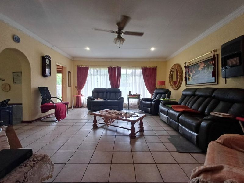 Spacious living room featuring tiled flooring, a ceiling fan, and a wall-mounted heater, offering a comfortable and functional layout.